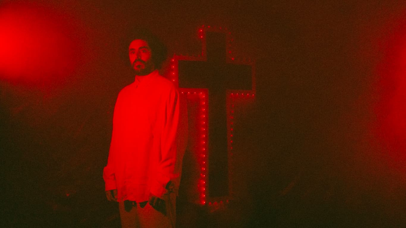 Imagen promocional de Los Acebos, con una cruz de luces roja al fondo y niebla
